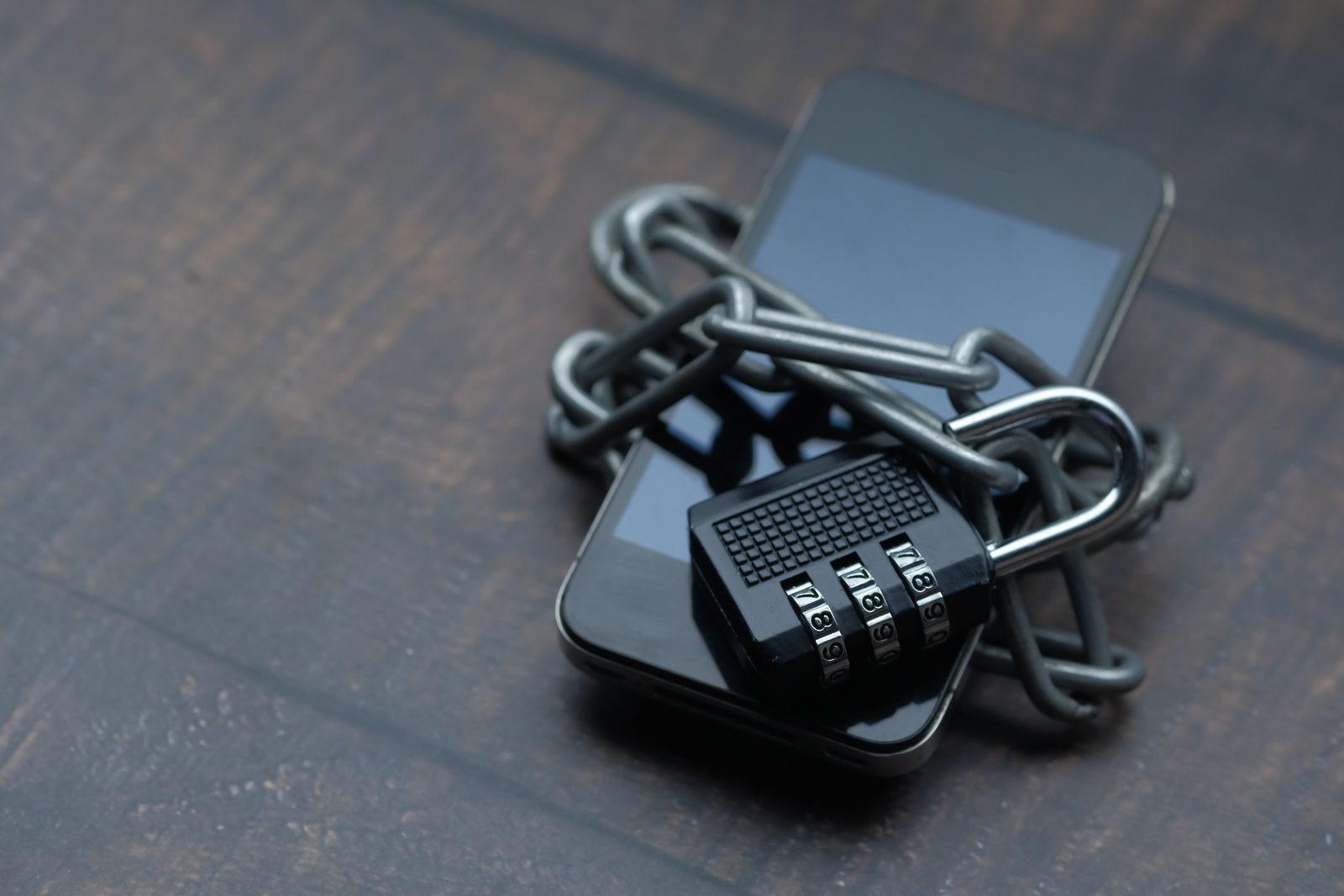A smartphone secured with a metal chain and combination padlock, symbolising WhatsApp account security and protection against account takeover